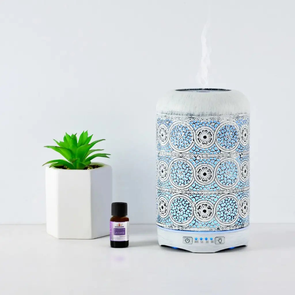 Activiva Metal Diffuser 260ml Vintage White with small green plant and oil bottle on white background.