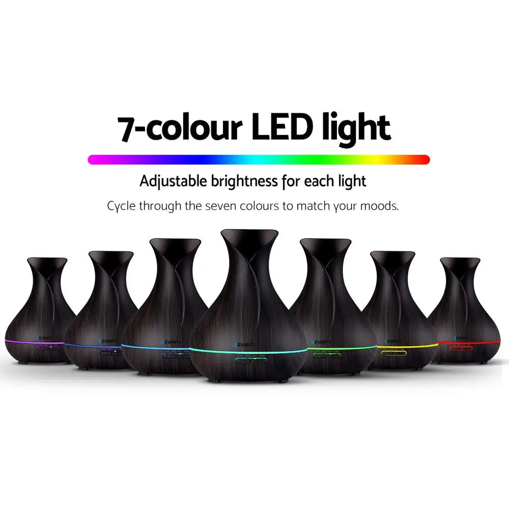 7 different coloured lights dark wood devanti 4 in 1 diffusers sitting in v shape on white background.