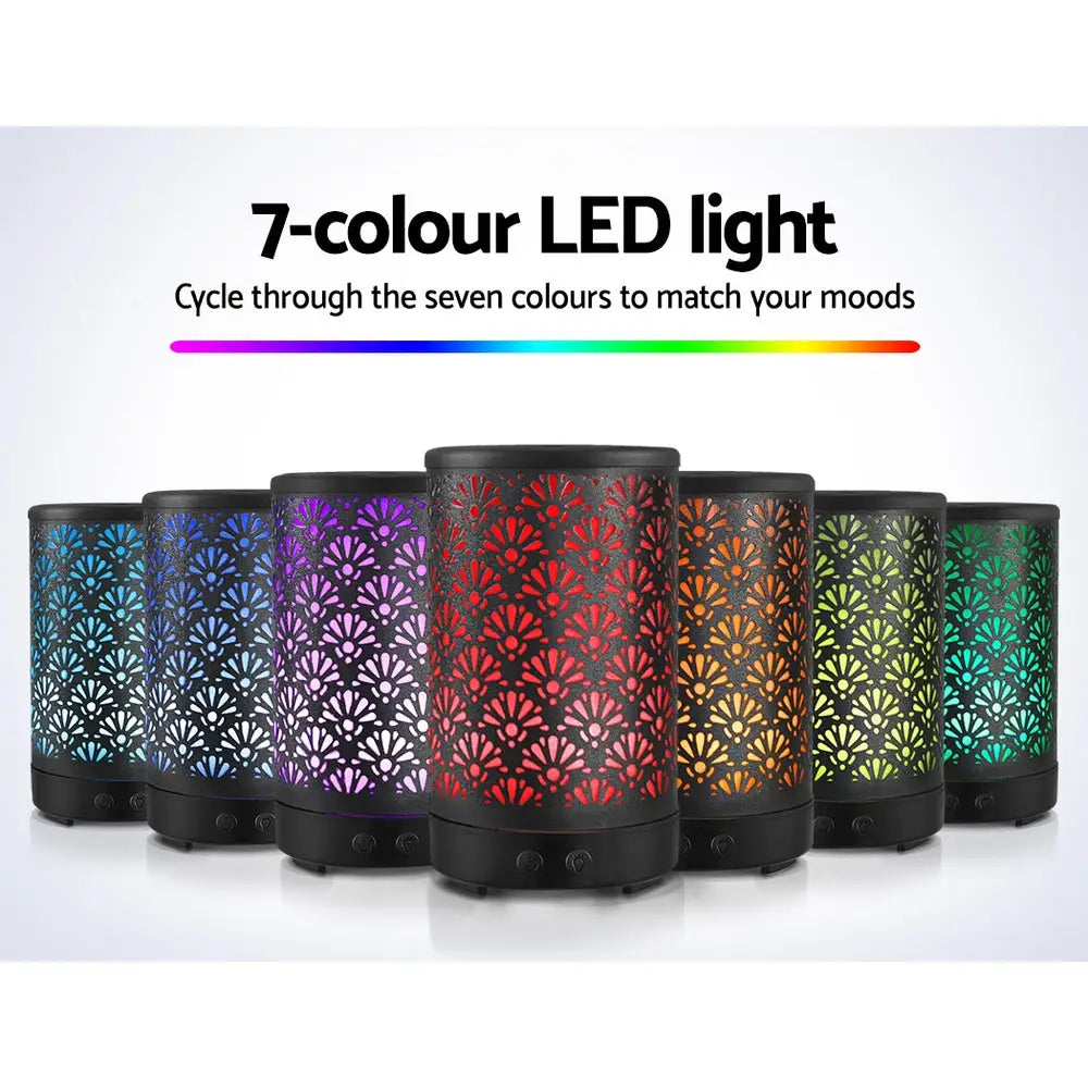 7 different led light colours of the devanti black decorative metal diffuser standing in v shape on white background.