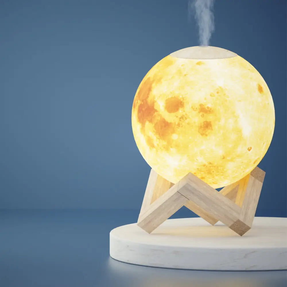 white round Moon Lamp Diffuser with yellow light on white round table with blue background.