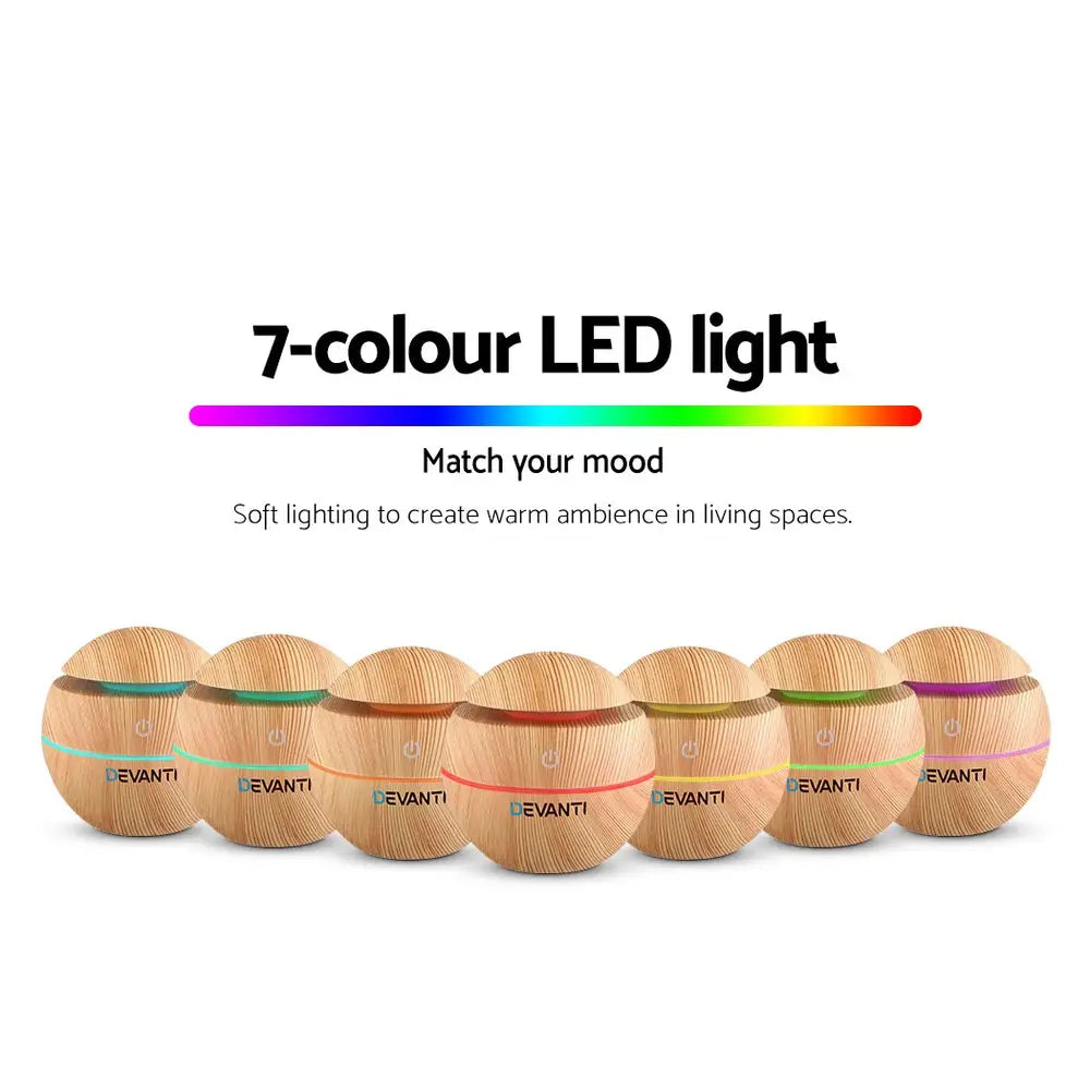 7 different coloured led lights of the devanti spherical humidifier in light wood grain standing in v shape on white background.